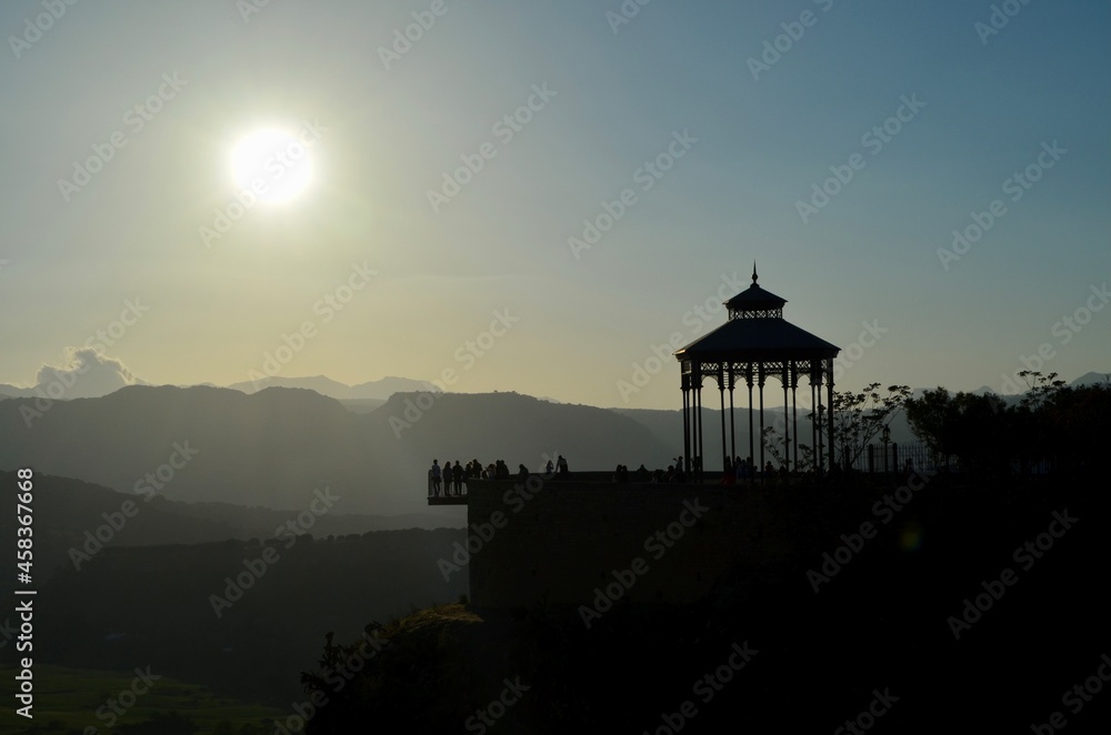 Sombra de un templete de un mirador en un acantilado con el sol de fondo