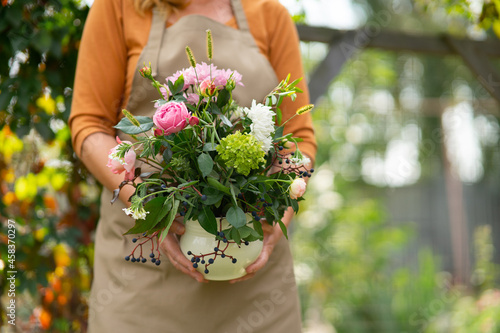 Woman is holding a flower pot with a hand-made bouquet of flowers from a home flower bed. Close-up of flowers in a bouquet.