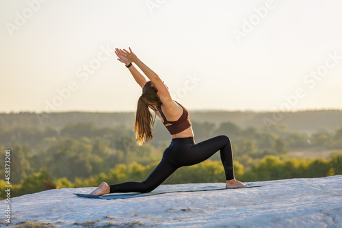 Young fitness woman doing yoga outdoors at sunset