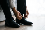 The groom wears shoes in the morning before the wedding ceremony. Male style.