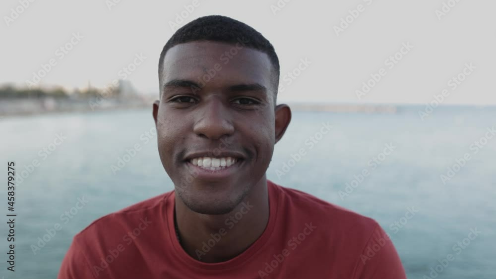 Close up portrait of smiling hispanic man looking at camera by the sea at sunset - Youth, millennial generation and hispanic people concept Close up portrait of smiling hispanic man looking at camera by the sea at sunset - Youth, millennial generation and hispanic people concept