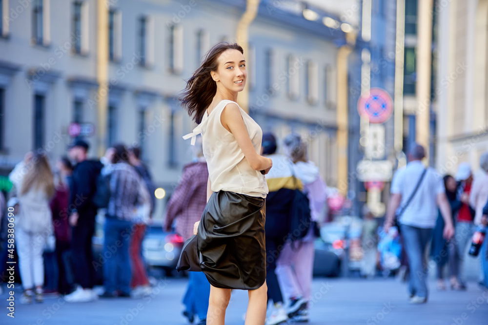 Happy slim woman in black skirt dances on crowded street.