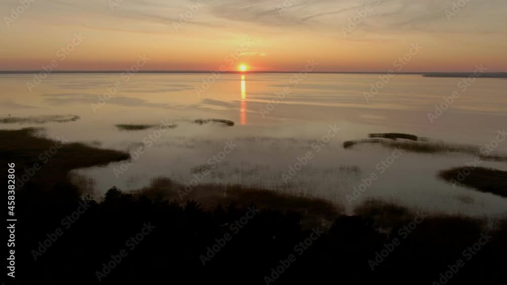 Aerial shooting of colorful sunset over a large beautiful lake and pine forest Aerial shooting of colorful sunset over a large beautiful lake and pine forest
