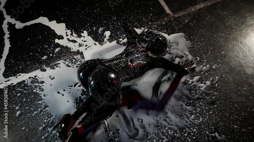 a woman in a black latex suit and high-heeled shoes smears a white liquid on the dark floor with her breasts. top view photo