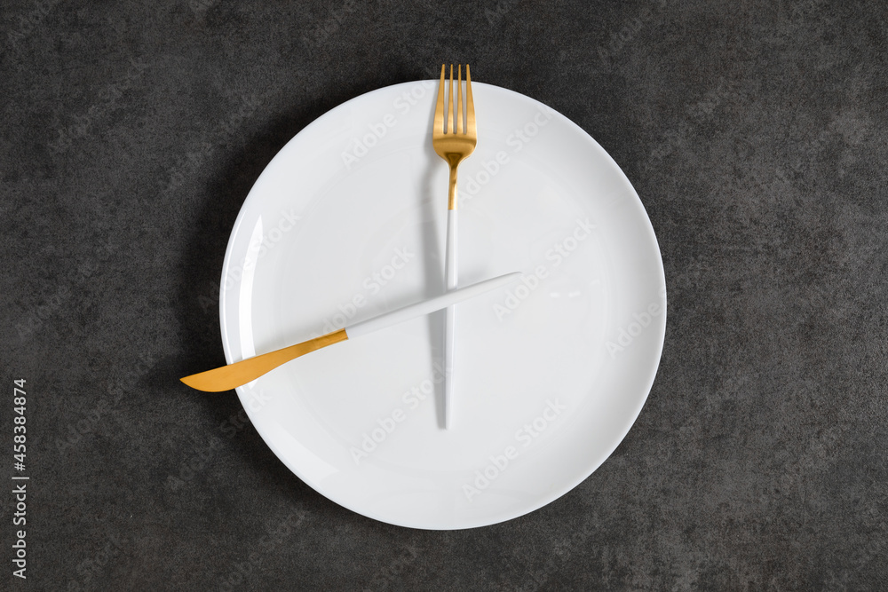 Concept of intermittent fasting, diet. Fork and knife crossed on plate. Flat lay, top view, copy space Concept of intermittent fasting, diet. Fork and knife crossed on plate. Flat lay, top view, copy space
