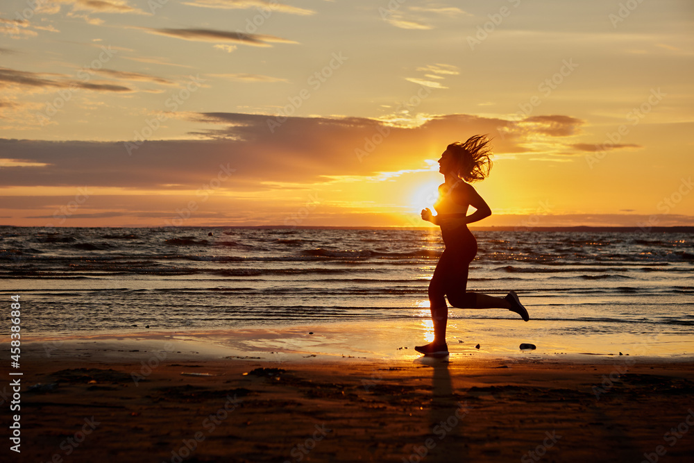 Woman runs on shore for being healthy during sunset.