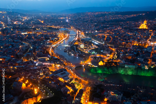 Picturesque general view from drone of Georgian city of Tbilisi on banks of Mtkvari River at spring dusk