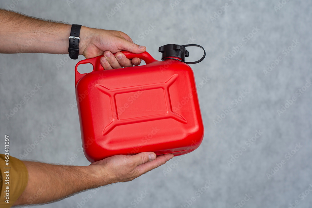 Man holds a red plastic gas canister in his hands. Man holds a red plastic gas canister in his hands.
