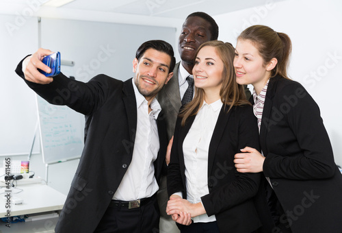 Happy group of business people making selfie in modern office