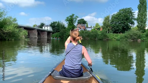 Girl paddling canoe on river wye on sunny day with blue skies photo