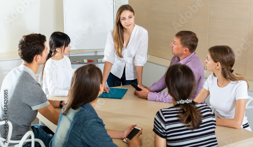 Successful young woman sharing business ideas with colleagues in meeting room. Concept of teamwork