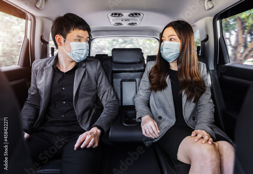 two business man and woman with face mask for protect covid-19 (coronavirus) while sitting at the back seat of car © geargodz
