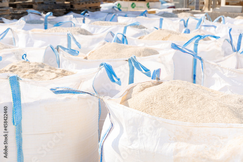 Bags with bulk construction materials standing in rows in outdoor storage. photo