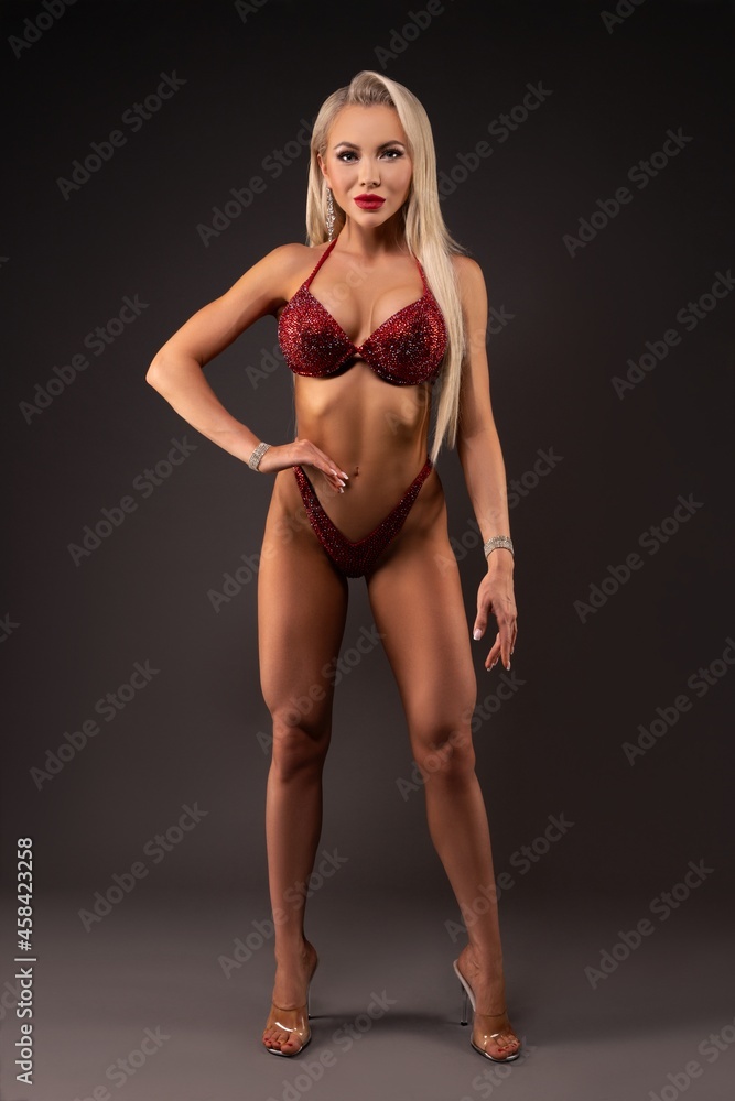 Athletic blond woman posing in lingerie in dark studio