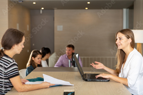 Young female employee of staffing agency consulting clients at meeting in informal office interior © JackF