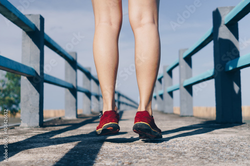Woman wear running shoe on to walking and running on nature green background.Health exercise.