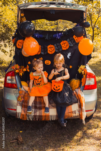 Children celebrating Halloween in trunk of car.