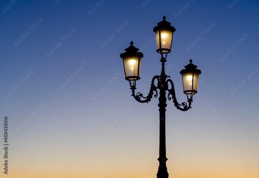 Street lamp lit in the blue sunset sky