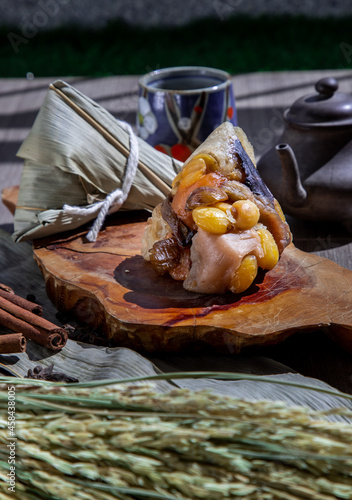 Obraz na płótnie Chinese rice dumpling (Zongzi) shaped pyramidal wrapped by leaves ingredients on wooden plate Served with chinese tea and chopsticks. Famous asian tasty handmade food in dragon boat (duan wu) festival w salonie