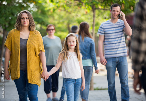 Cheerful mother with little glad daughter walking in the park