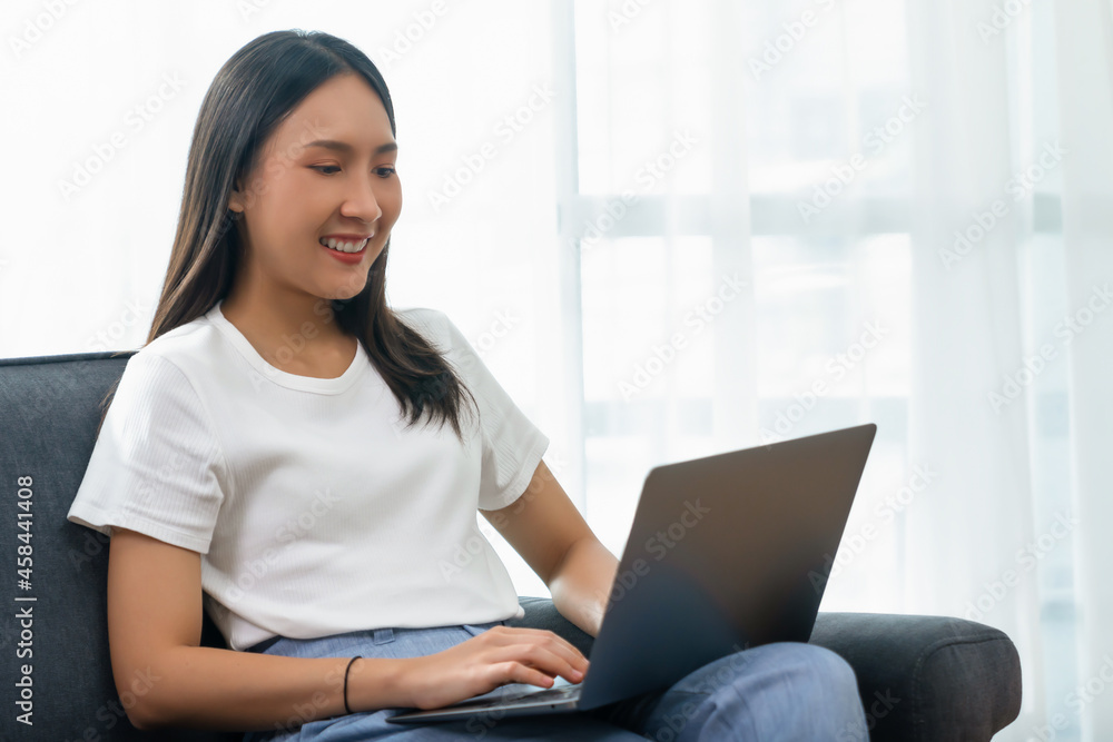 Beautiful asian woman using laptop and sitting on the sofa in living room. Beautiful asian woman using laptop and sitting on the sofa in living room.