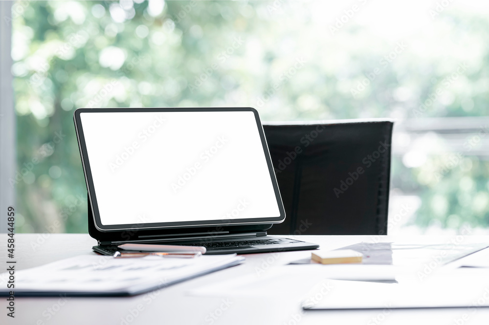 Blank screen tablet with magic keyboard and document on the table in modern office room. Blank screen tablet with magic keyboard and document on the table in modern office room.