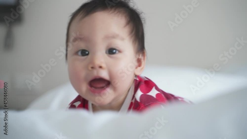 portrait of asian baby infant 8 months old playing on bed at home. happy innocence baby kid smile happily. sucking hand age baby portrait crawling copy space provided. smiling baby laugh in bedroom.