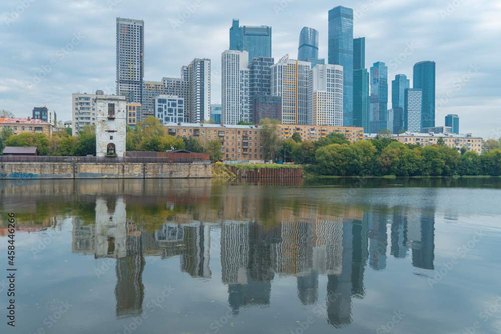 View from the embankment of the Moskva River to a residential area with skyscrapers Moscow City in the background with the reflection of buildings in the water