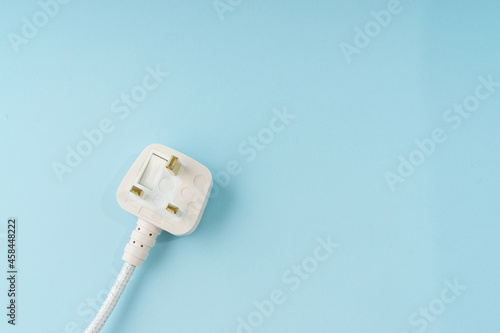 Three pin plug on light blue background with a copy space. photo