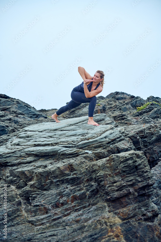 woman practicing yoga on some rocks