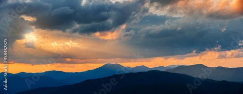 Majestic sunset sky over blue mountains landscape in cloudy day of rainy season