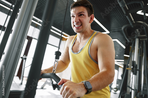 Young bodybuilder doing heavy weight exercise for biceps in a gym