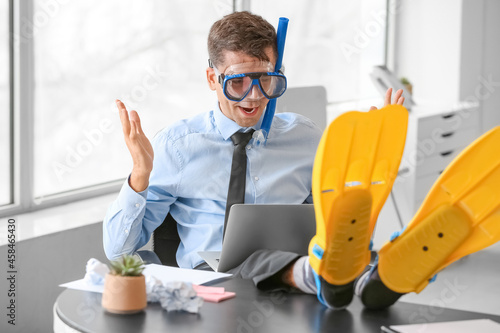 Happy man with snorkeling mask and paddles working in office