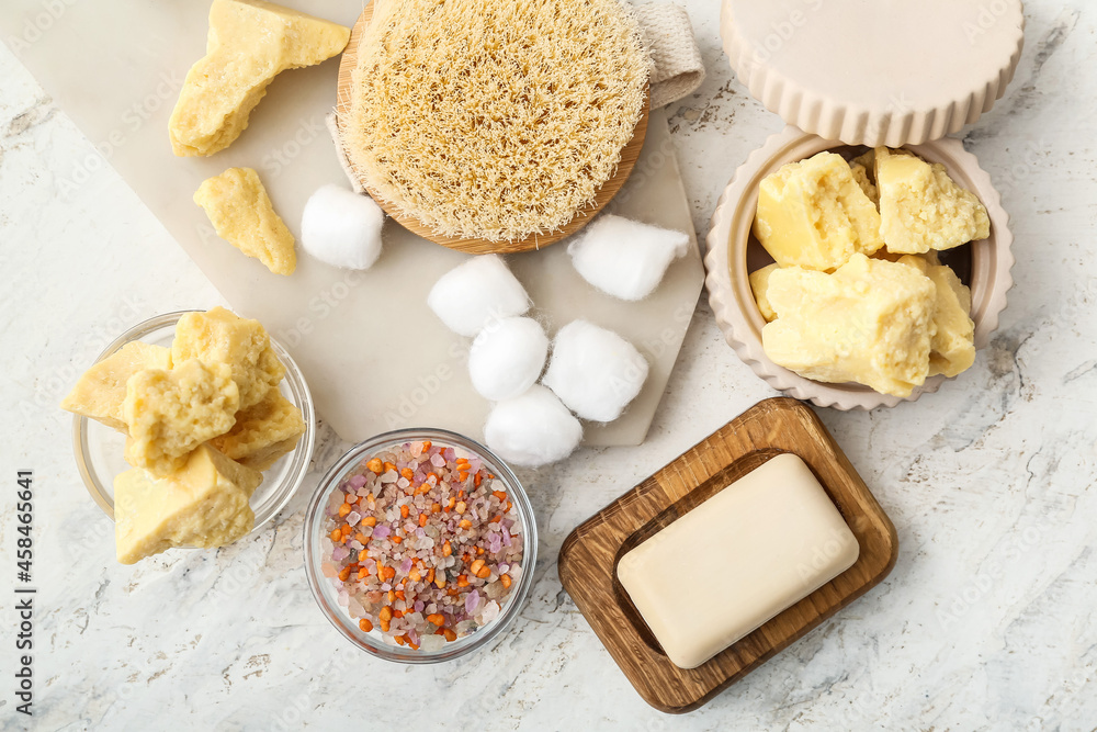 Composition with cocoa butter and bath supplies on light background