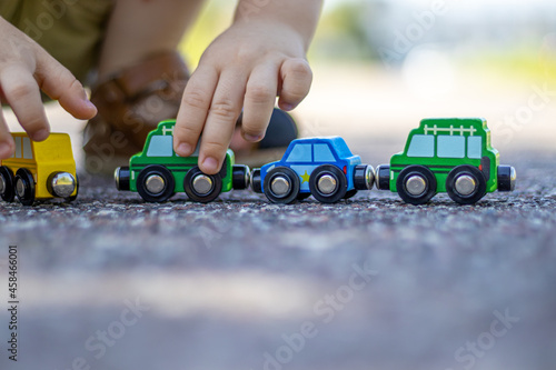 A kid is playing with a train made from wood, with magnet connections are on the asphalt, outside. Concept: playing outdoor, summertime, eco toys. photo