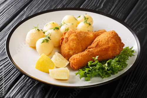 Photography Austrian Fried Chicken Backhendl served with lemon and new potatoes close up in the plate on the table