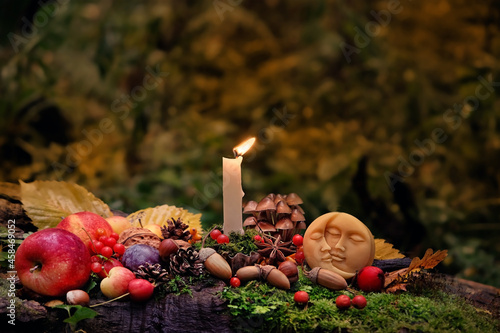 Moon amulet, candle, autumn leaves, fruits, berries, nuts in mysterious forest. Wiccan altar for Mabon sabbat. autumn equinox holiday. Witchcraft, esoteric spiritual ritual photo
