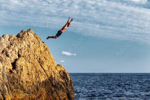A man jumps into the sea from a high cliff