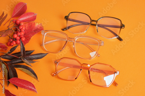 eye glasses nad red autumn leaves on orange background copy space