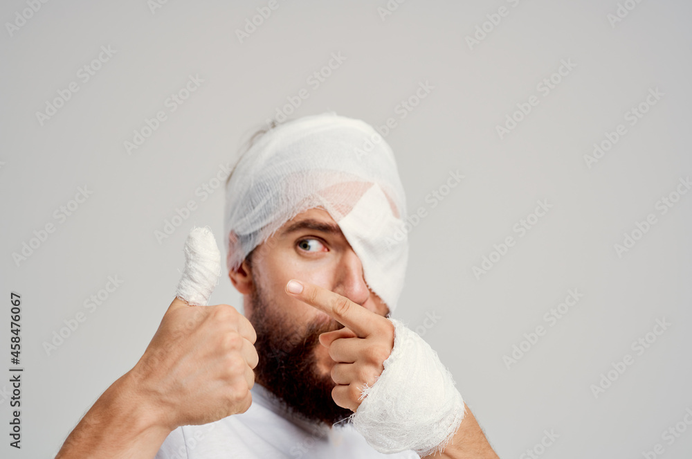 bearded man with bandaged head and eye hospitalization light background bearded man with bandaged head and eye hospitalization light background