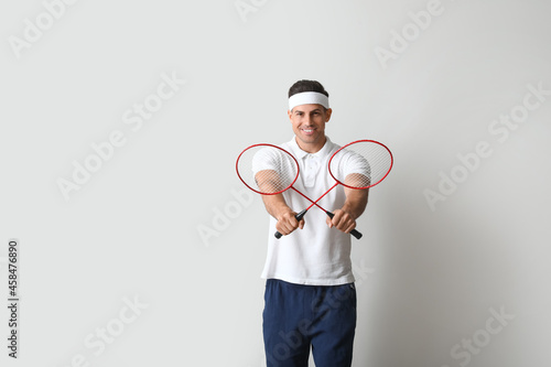 Sporty male badminton player on light background © Pixel-Shot