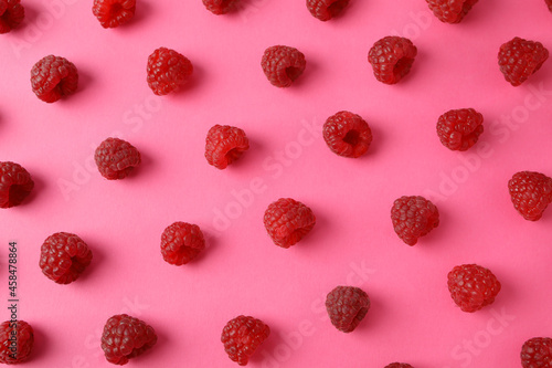 Flat lay composition with red juicy raspberries on a pink background