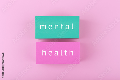Creative flat lay with blue and pink blocks with written mental health text on bright pink background. Concept of world mental health day, mental health assessment and awareness