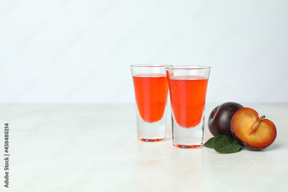 Plum brandy shots and ingredients on white textured table Plum brandy shots and ingredients on white textured table