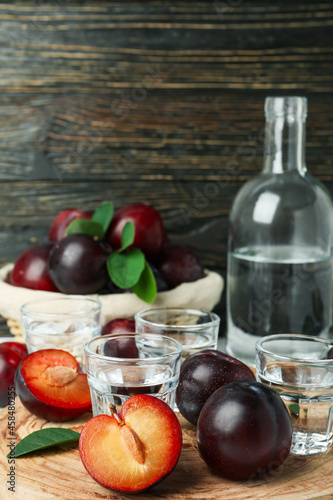 Concept of alcohol with plum vodka against wooden background