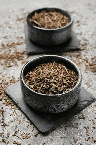 Bowl of dry hojicha green tea on grunge background