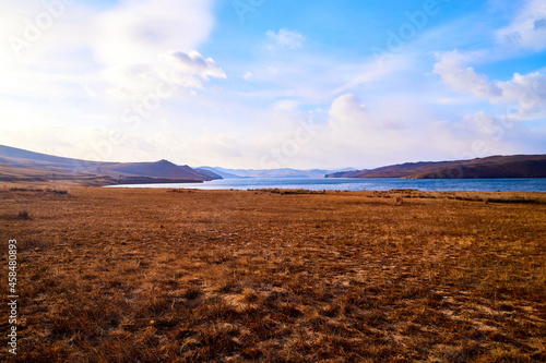 Nature landscape with golden field, wather, hills and blue sky with white clouds in a day or a evening