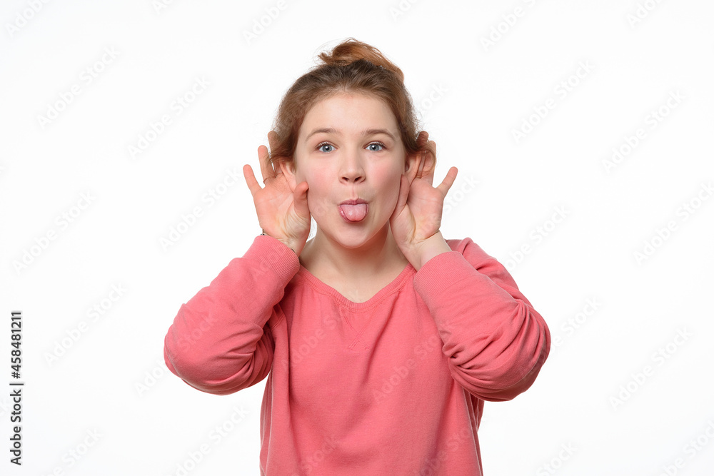Close-up portrait of cheerful young girl making funny face and showing her tongue. White background Close-up portrait of cheerful young girl making funny face and showing her tongue. White background