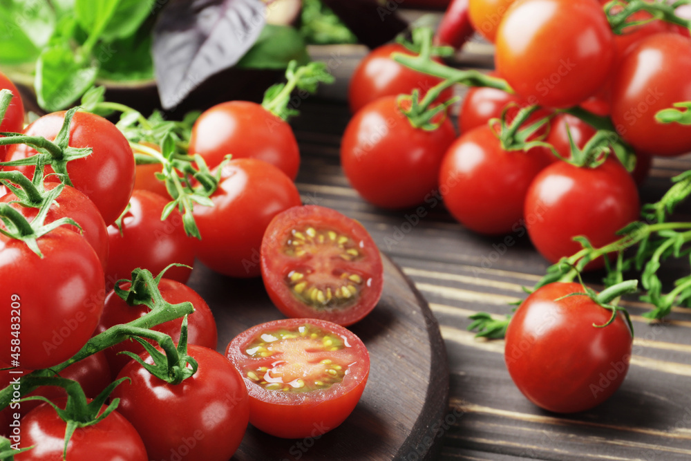Composition of fresh ripe branches of cherry tomatoes, thyme, basil, rosemary, spices on a wooden textured background Composition of fresh ripe branches of cherry tomatoes, thyme, basil, rosemary, spices on a wooden textured background