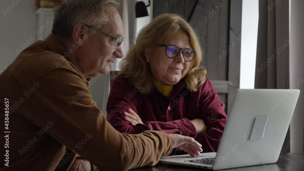 two elderly people surfing internet on laptop computer at home. 4K video two elderly people surfing internet on laptop computer at home. 4K video